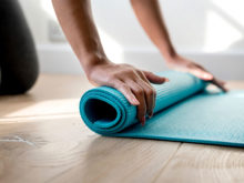 kvinna-rullar-upp-yoga-matta-efter-traningspass